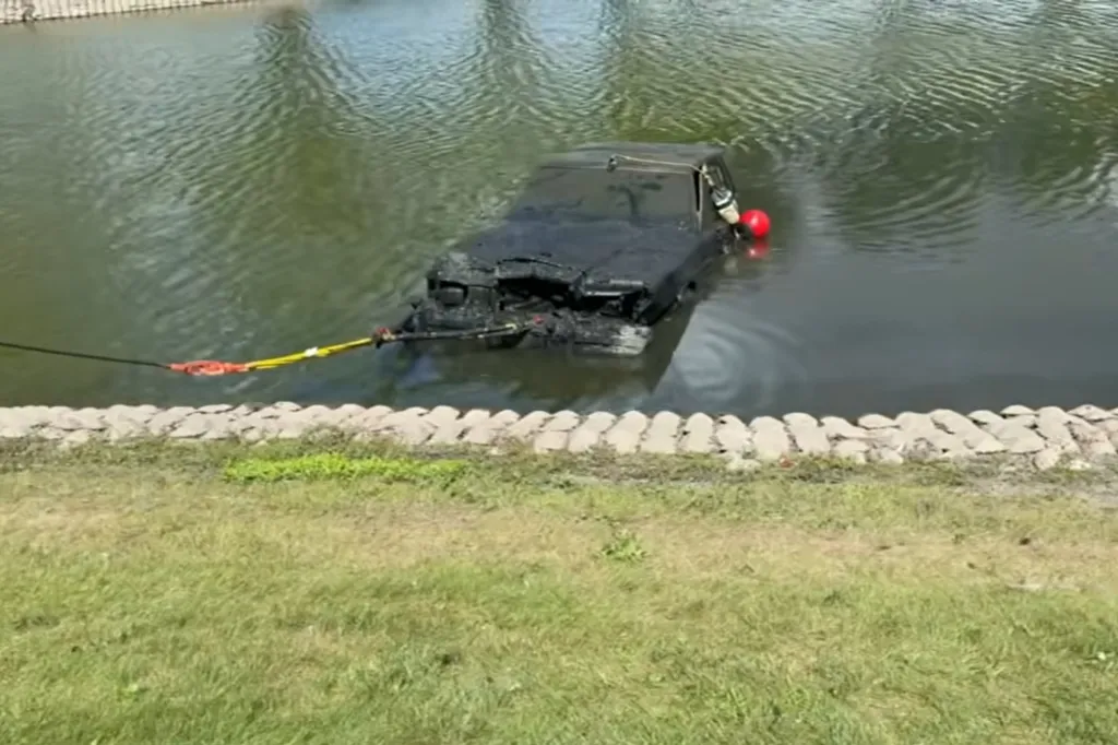 A car partially submerged in water, being towed out.