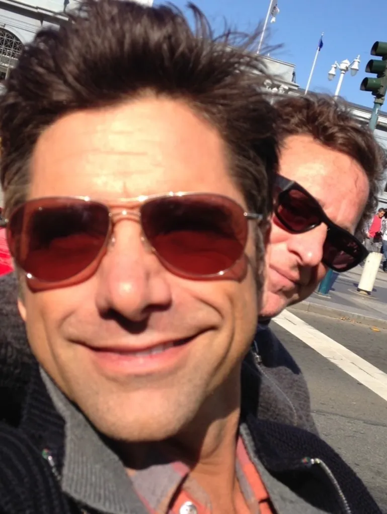 John Stamos and Bob Saget wearing sunglasses in a selfie.