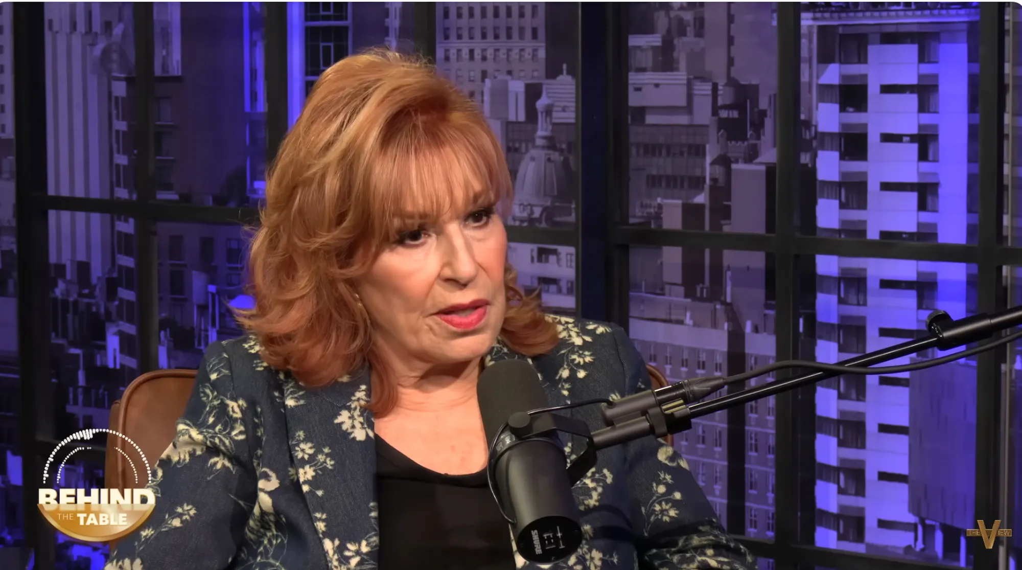 Joy Behar speaking into a microphone during a podcast.