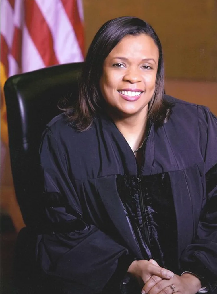 Judge Eleanor Ross of the United States District Court for the Northern District of Georgia, wearing a judicial robe, smiles at the camera with an American flag behind her.
