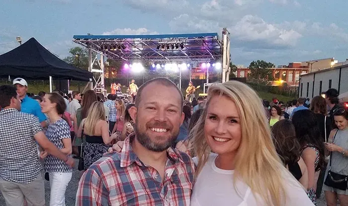 Justin and Sarah Taylor Brigham smile at a concert.