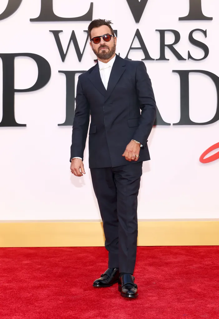 Justin Theroux in a dark suit, white shirt, and sunglasses on a red carpet.