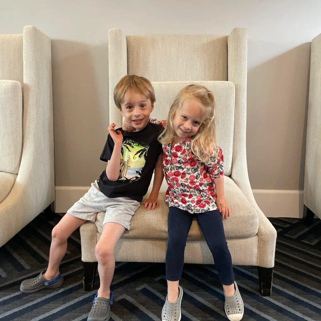 Kai MacAusland (left) and Ella MacAusland sit together on a chair.
