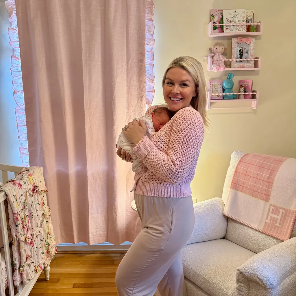 Karoline Leavitt holding her newborn baby Viviana in a pink-themed nursery.