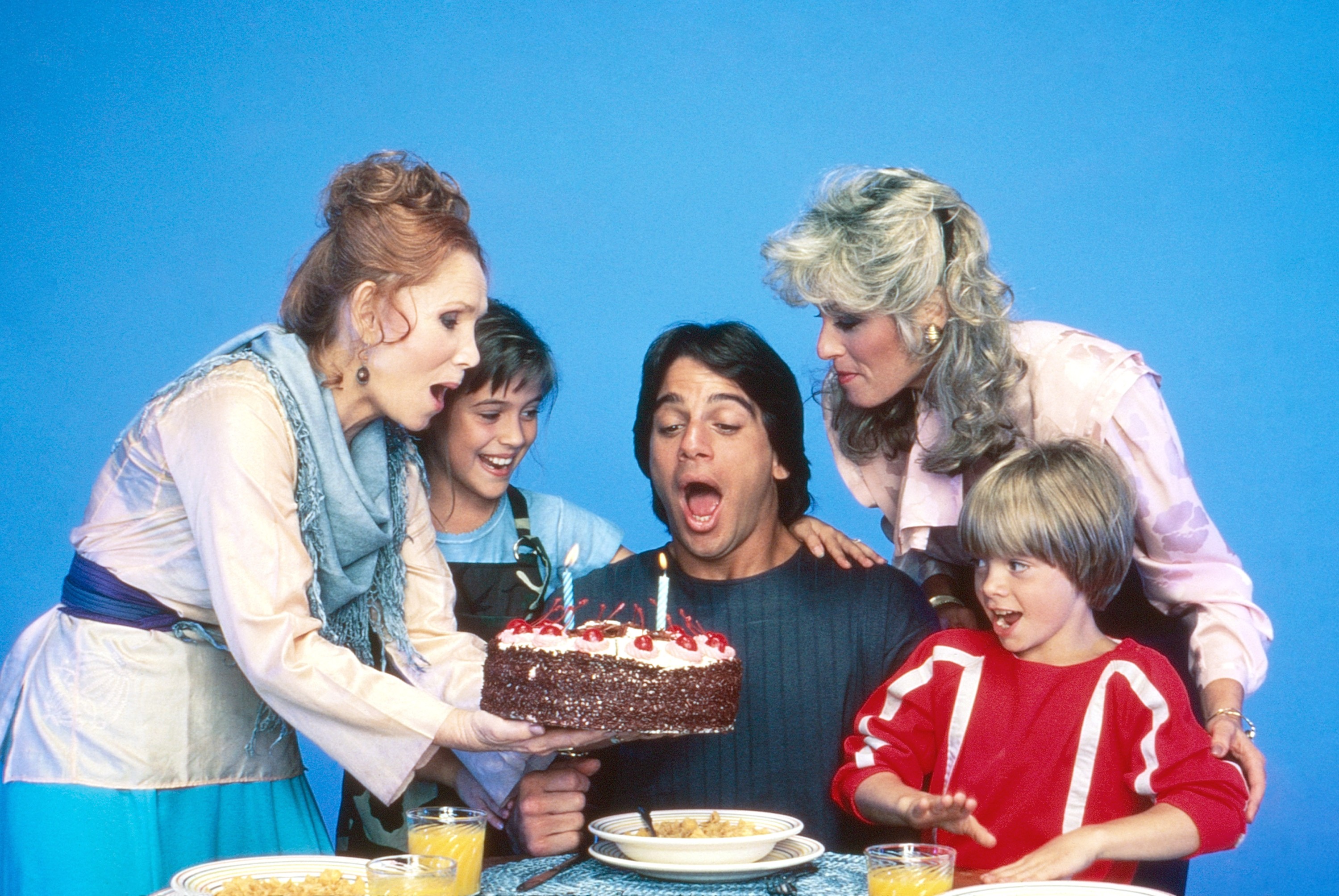 Cast shot of Katherine Helmond, Alyssa Milano, Tony Danza, Judith Light, and Danny Pintauro celebrating a birthday on the set of *Who's the Boss?*
