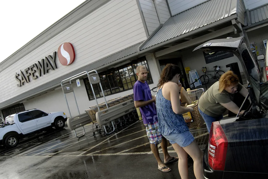 People loading groceries into a car outside a Safeway store.