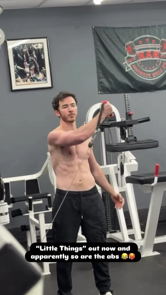 Kevin Jonas working out shirtless in a gym.