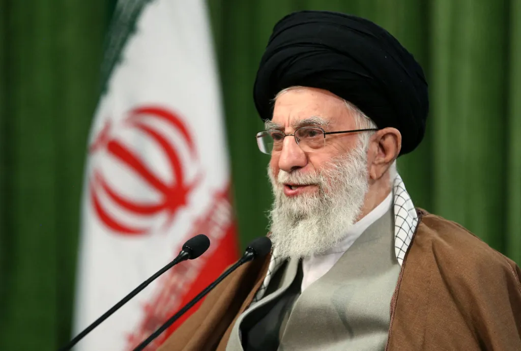 Ayatollah Ali Khamenei giving a televised speech with the Iranian flag in the background.