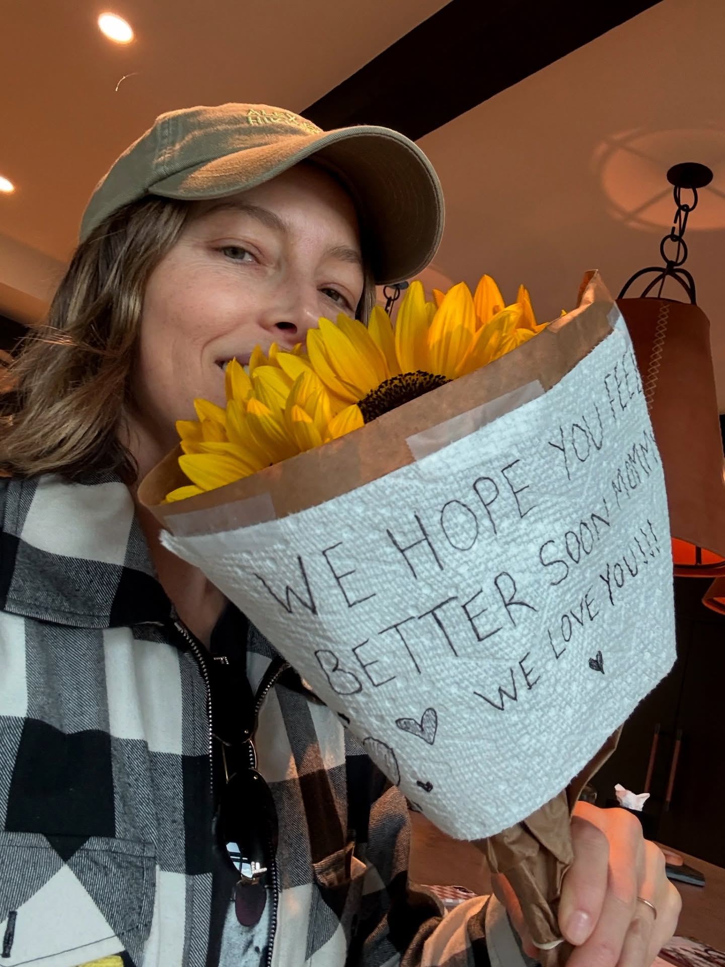 Jessica Biel holding a bouquet of sunflowers with a note that says 