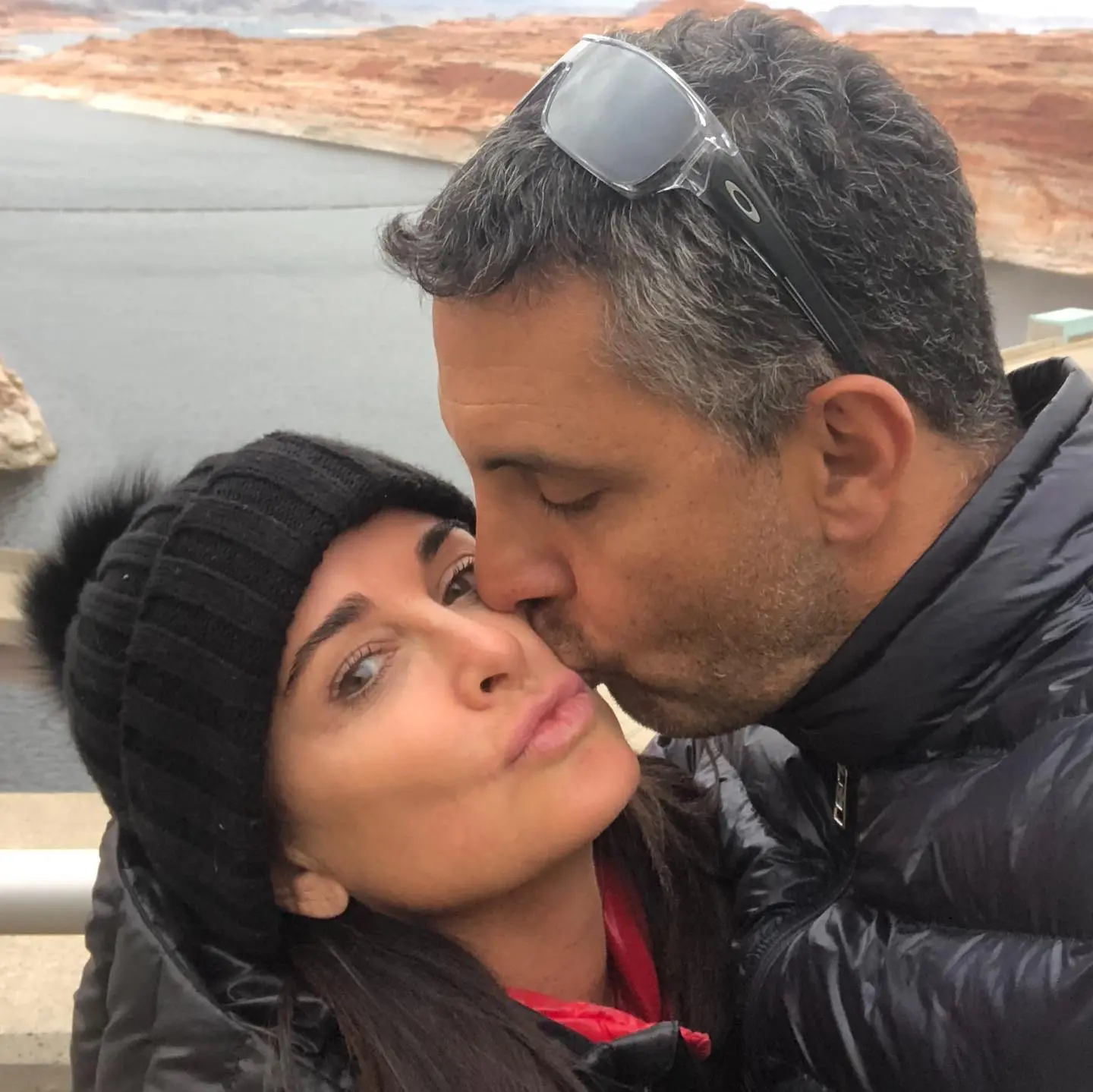 Kyle Richards and Mauricio Umansky embracing outdoors, with Umansky kissing Richards on the cheek.