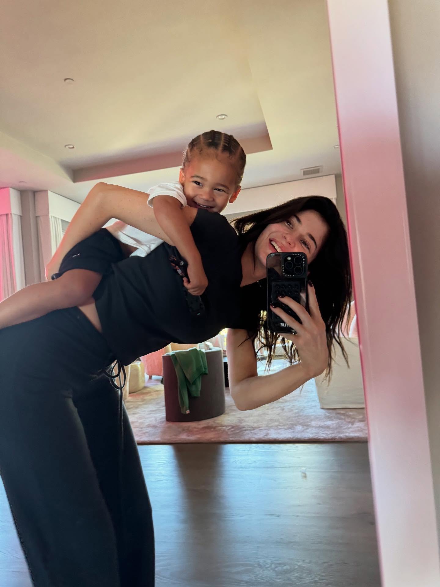 Kylie Jenner taking a selfie with her son, Aire, on her back.