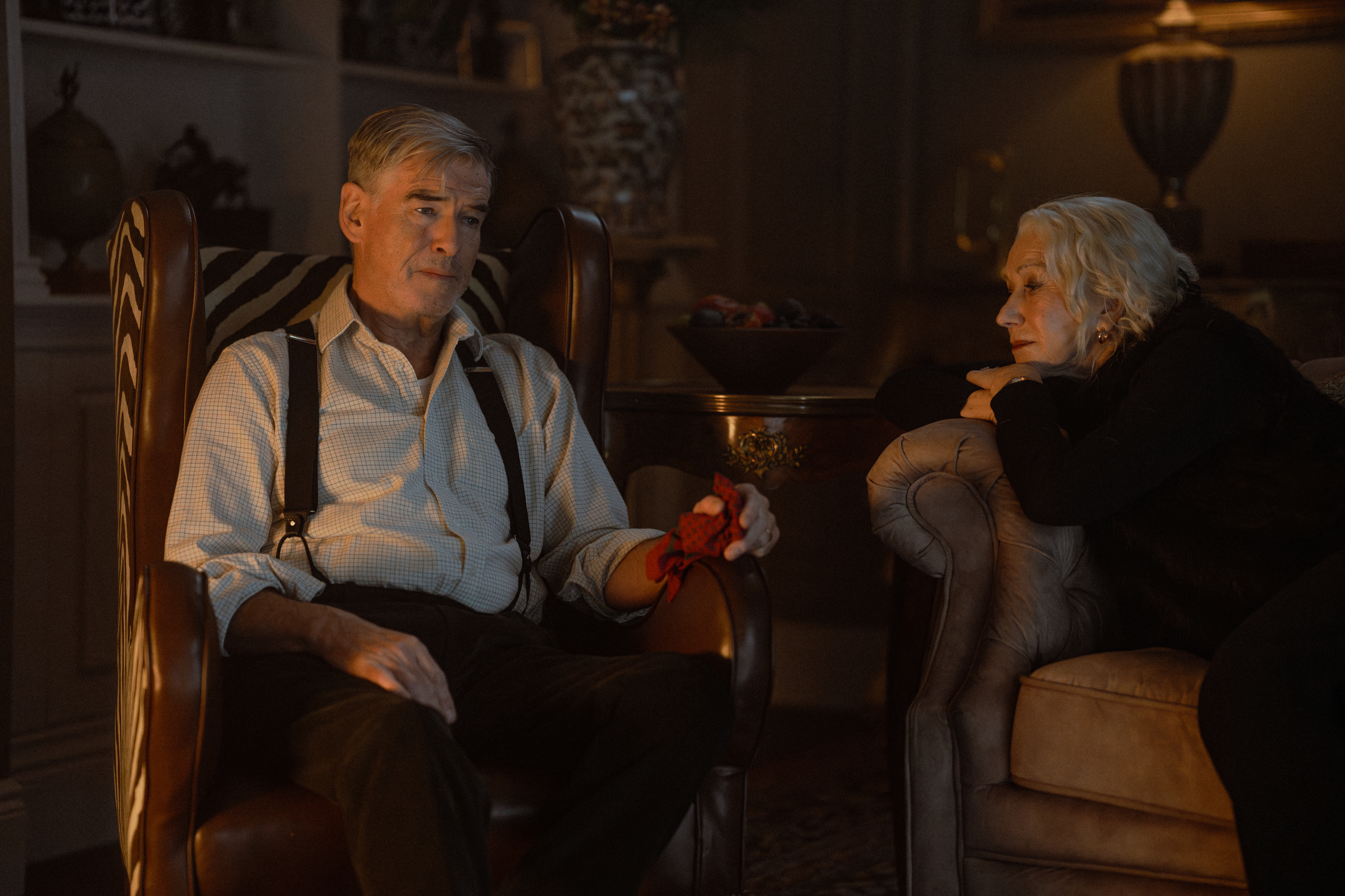 Pierce Brosnan as Conrad Harrigan and Helen Mirren as Maeve Harrigan sit in separate chairs.