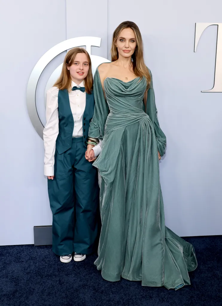 Vivienne Jolie, in green pants, green vest, white shirt and green bow tie, and Angelina Jolie, in a green gown, on the red carpet at the 77th Annual Tony Awards.