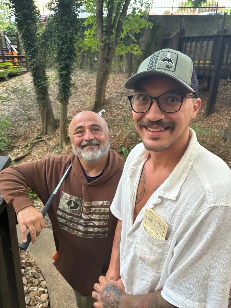 John and Jacob smiling outdoors, with Jacob holding a golf club.