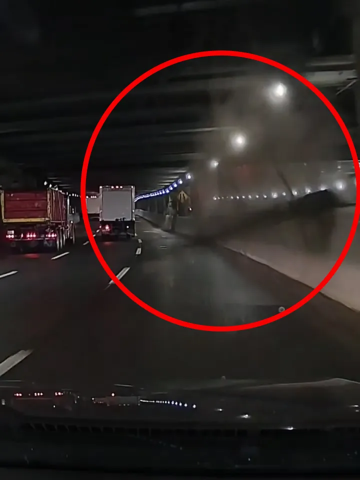 Debris falling from the ceiling of a tunnel, with two trucks driving ahead.