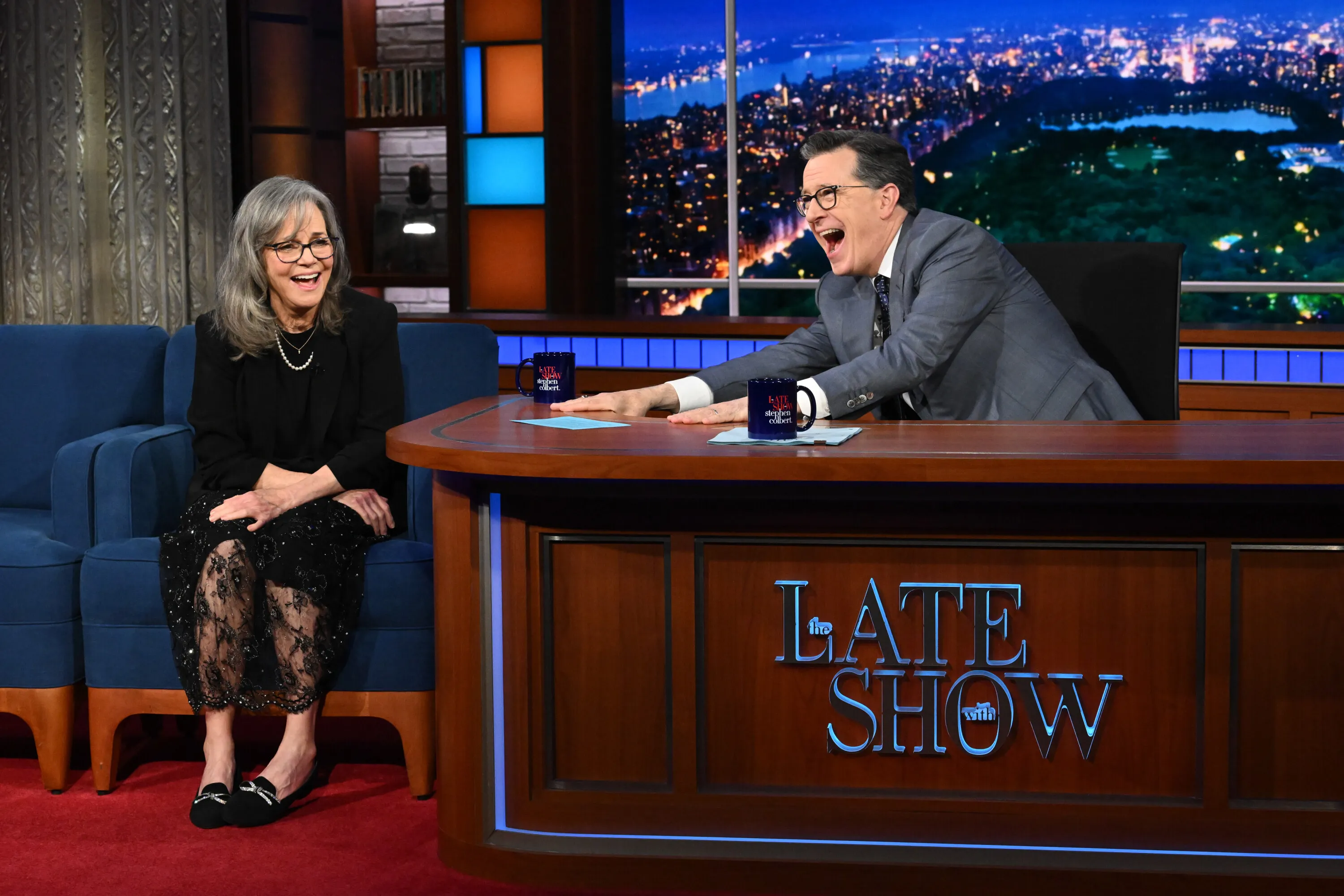 Stephen Colbert laughing heartily while Sally Field smiles next to him during 