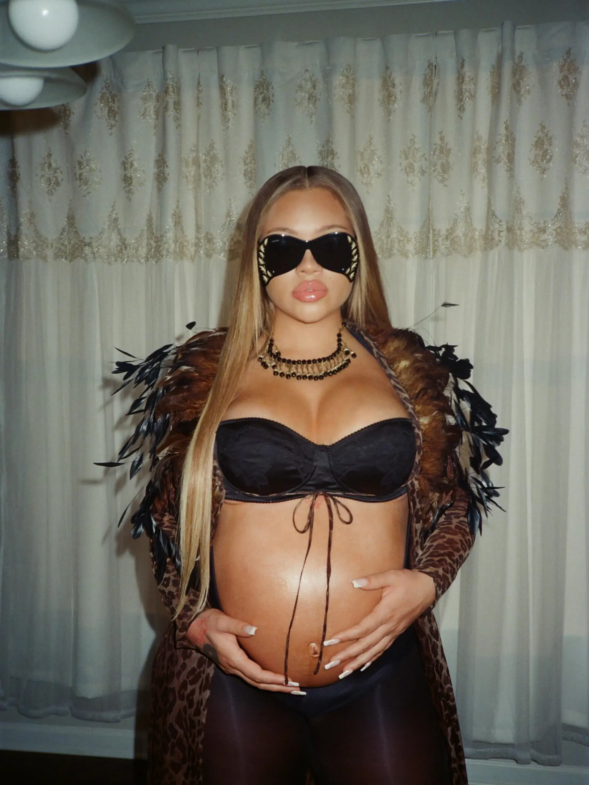 Latto posing with her pregnant belly, wearing a leopard print robe and sunglasses.