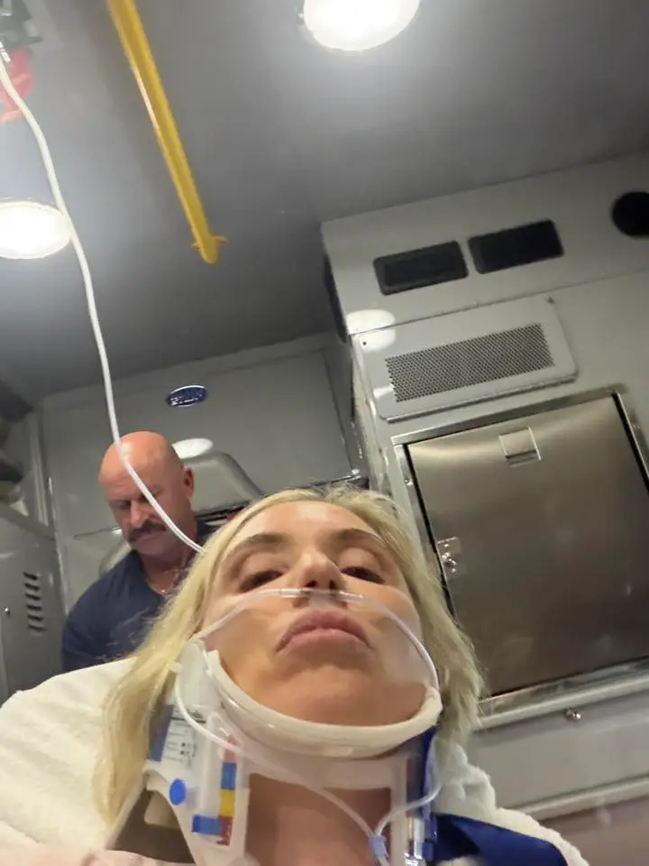 Laura Clery in an ambulance with a neck brace and oxygen cannula after a fridge accident.