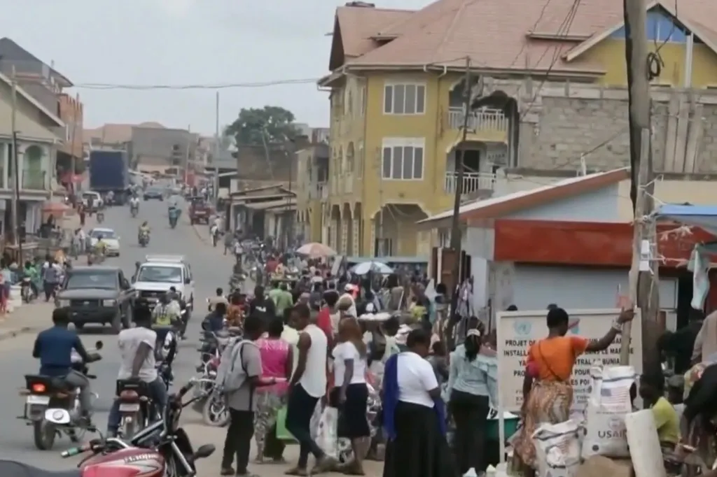 A busy street in the Democratic Republic of Congo with people, motorcycles, and vehicles.