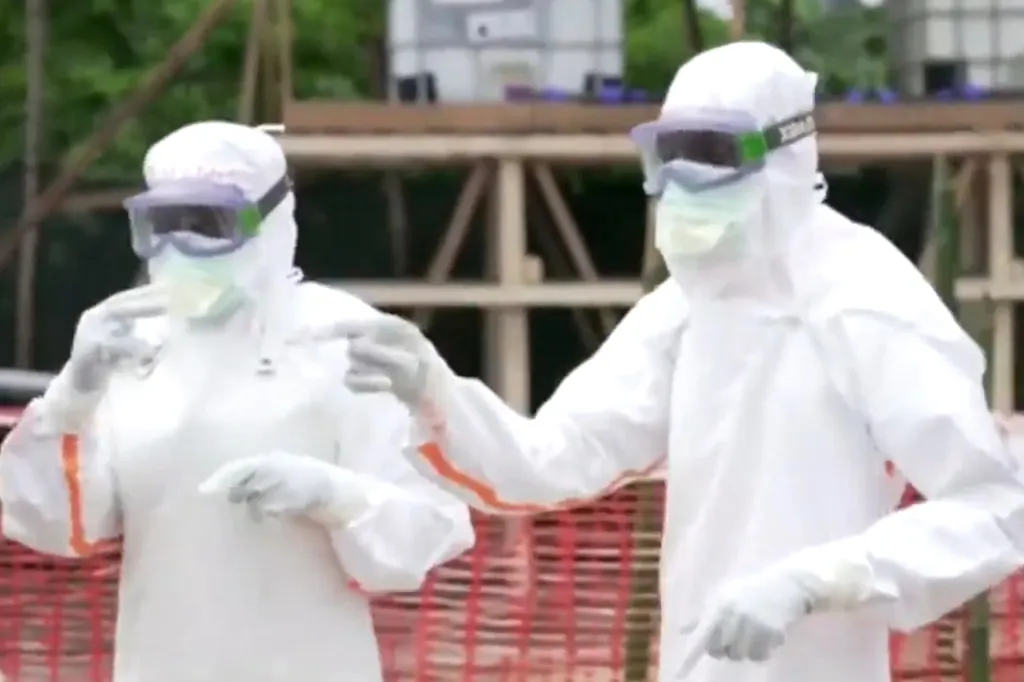 Two people in white hazmat suits and goggles.