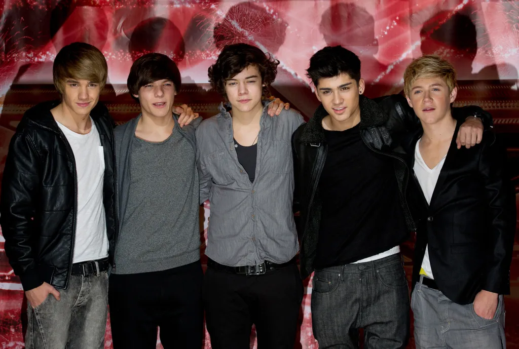 Liam Payne, Louis Tomlinson, Harry Styles, Zayn Malik, and Niall Horan of One Direction posing together at a press conference.