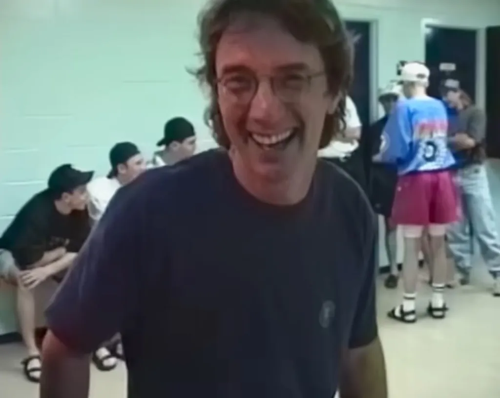 Martin Short laughing in a room with other people.