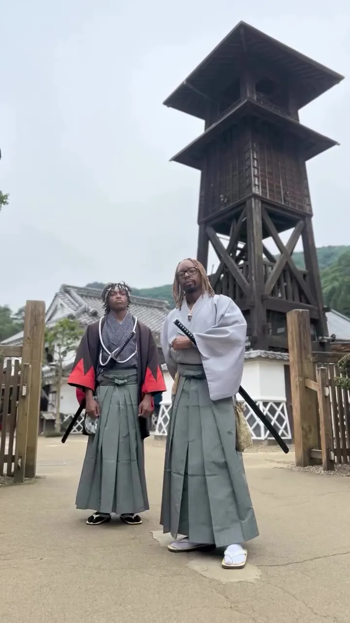 Lil Jon and his son, Nathan, dressed in samurai attire, standing in front of a traditional Japanese building.