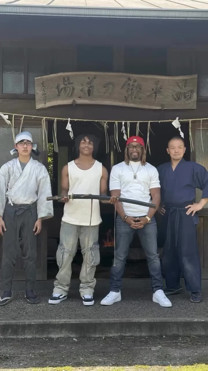 Lil Jon poses with his son and two Japanese men in front of a building.