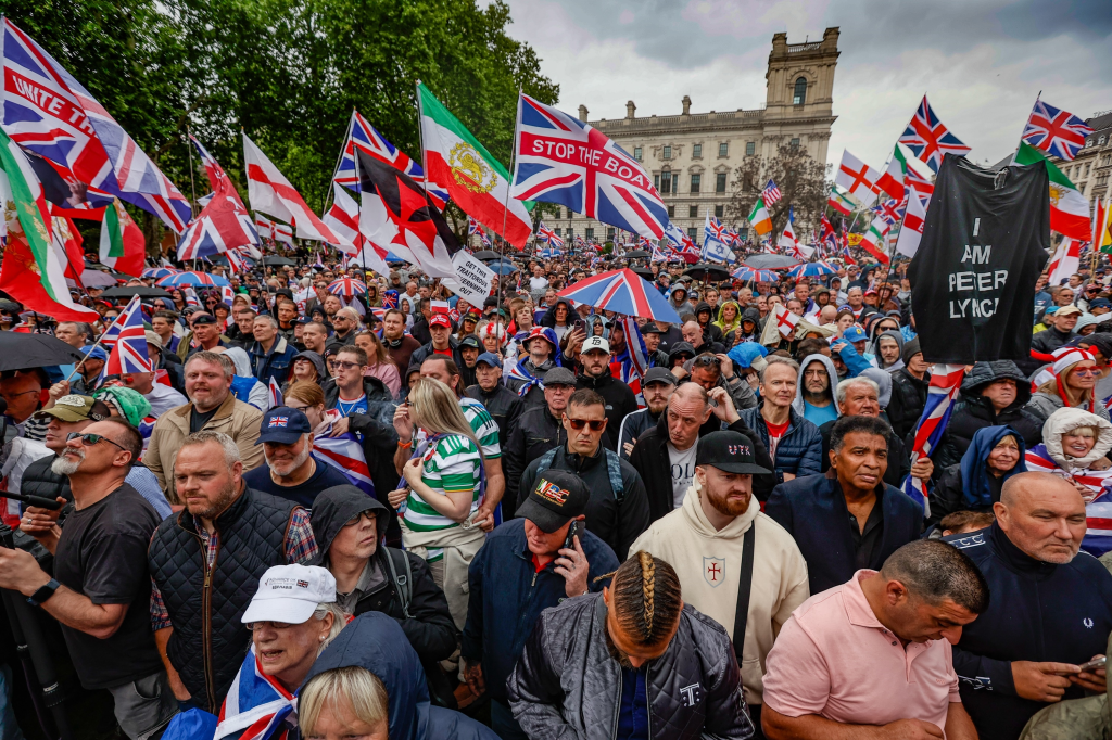 Crowds gathered at the Unite the Kingdom Rally in London, with many holding Union Jack flags, including one that reads 