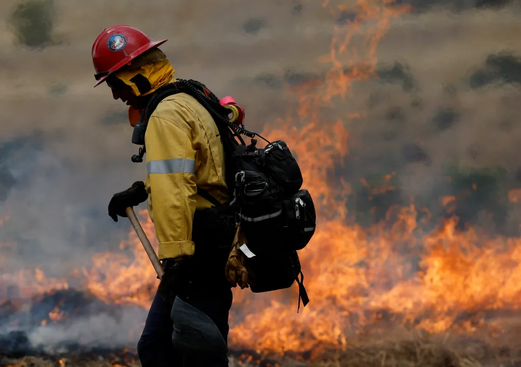 A Los Angeles County firefighter walks by burning grass during a wildland fire training exercise.