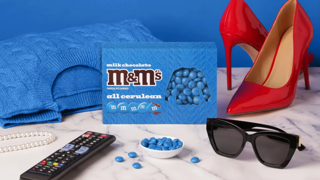 M&M's All Cerulean Pack with a blue sweater, red high heels, sunglasses, pearls, and a remote control.