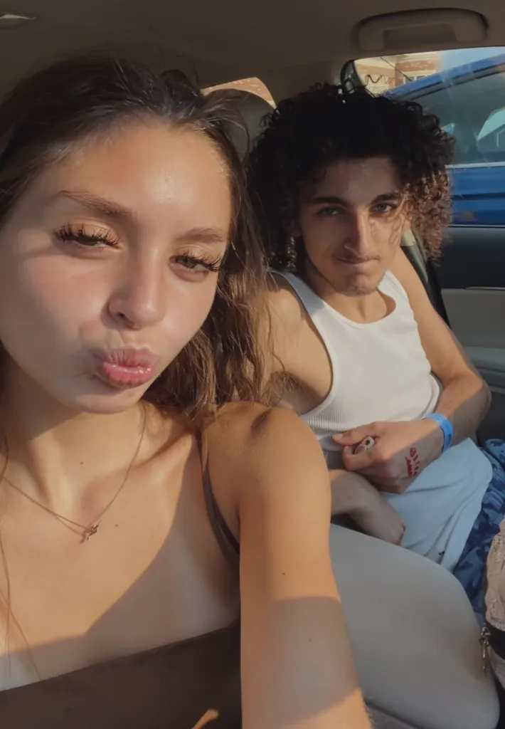 Mackenzie making a kissy face while Dom looks at the camera in a car.