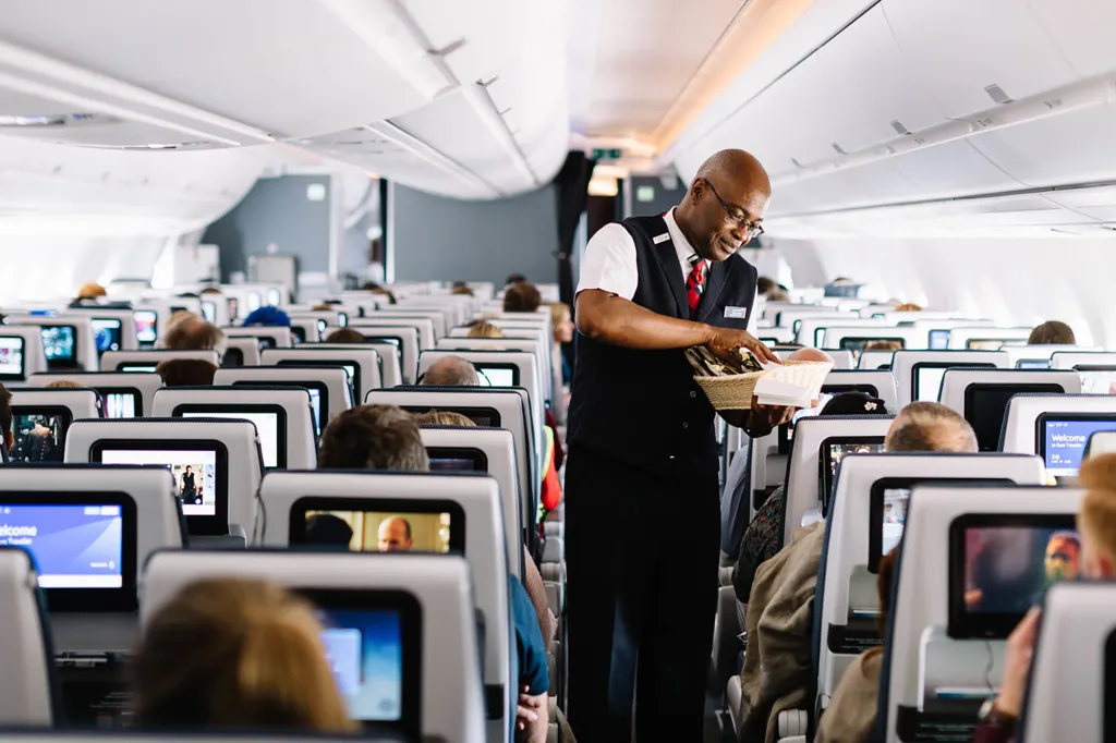 A flight attendant offering passengers snacks from a basket on an airplane.