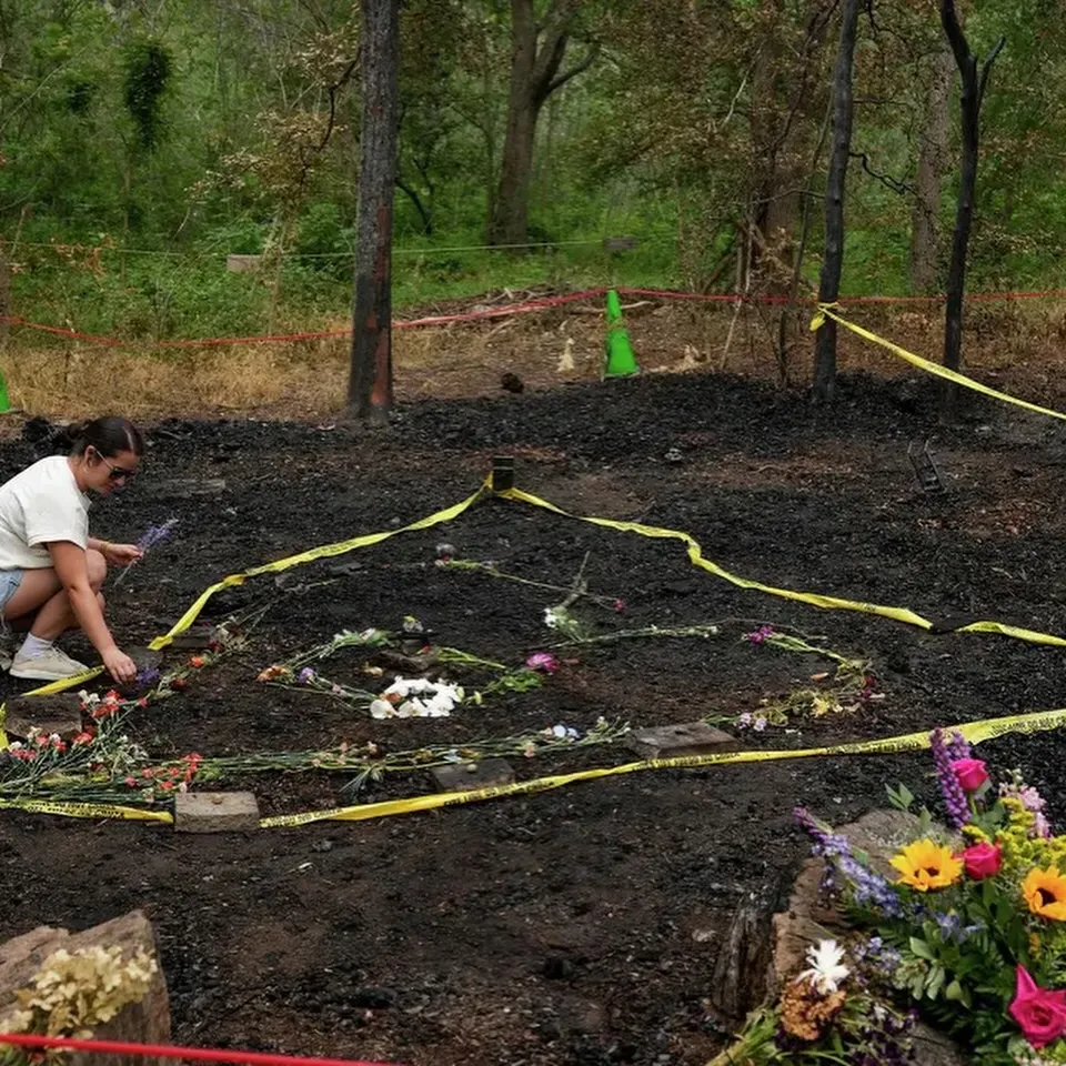 A person placing flowers on the charred ground where Malin's Fountain was destroyed by fire.