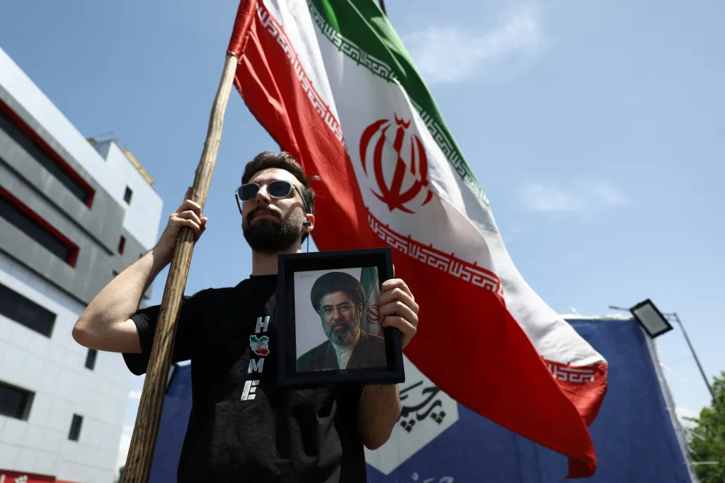 A man holds an Iranian flag and a picture of the new Supreme Leader Mojtaba Khamenei in Tehran, Iran.