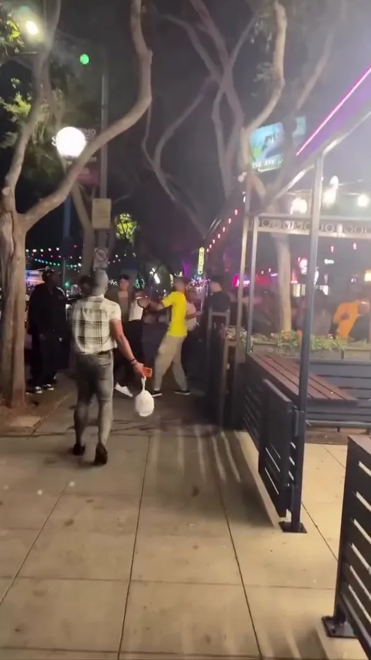 A group of men fighting on a sidewalk in West Hollywood's rainbow district at night.