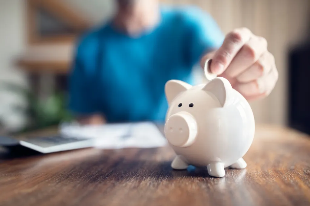 Man putting a coin into a white piggy bank.