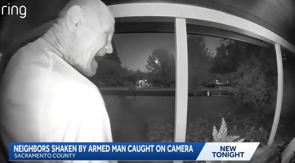 A man captured on a doorbell camera standing at a door with a knife.