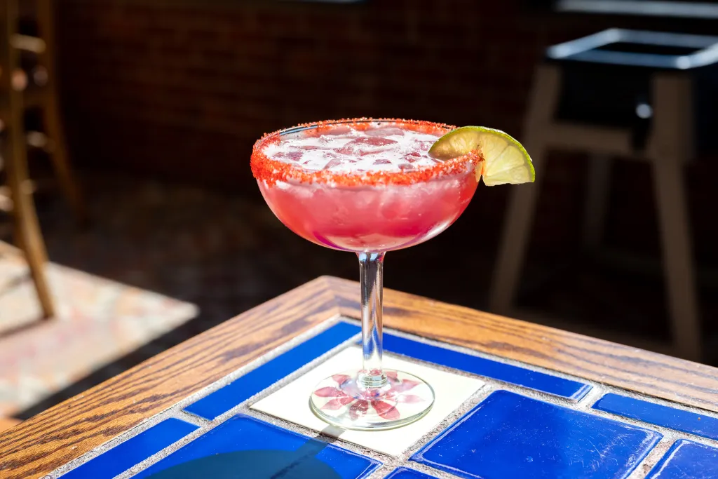 Margaritas Mexican Restaurant mothers day deal featuring a bright pink margarita with a lime wedge on a tiled table.