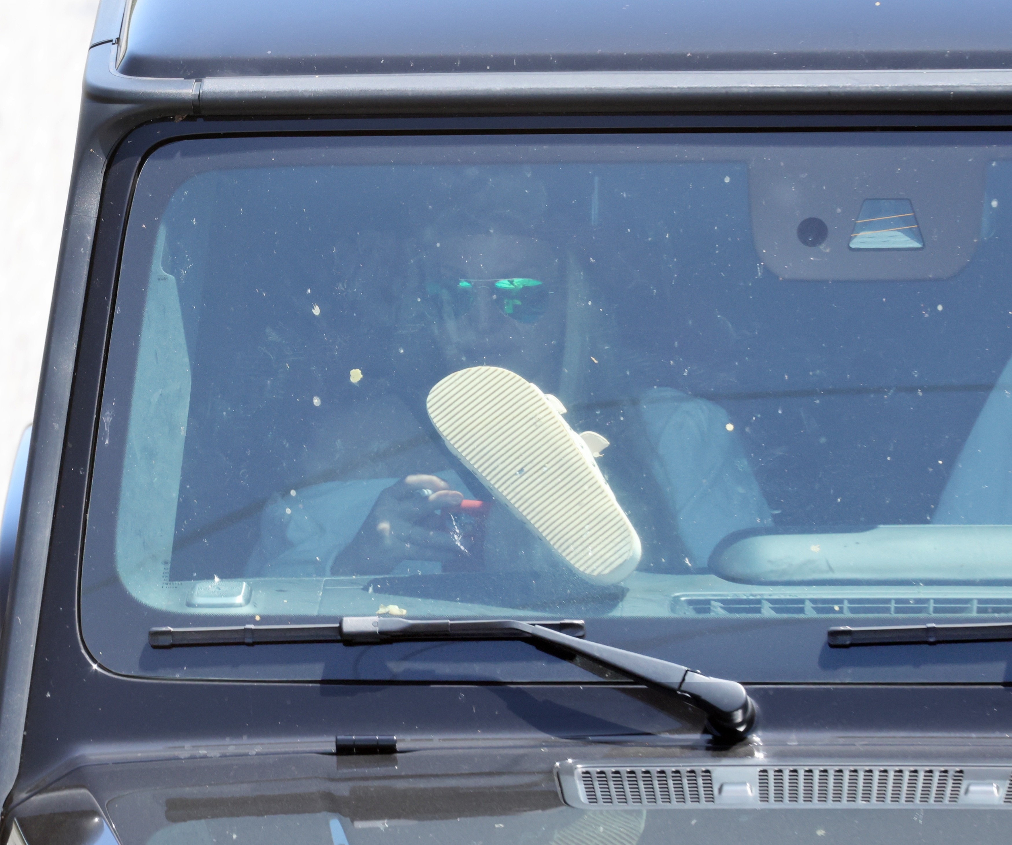 Britney Spears smoking a cigarette with her foot on the dashboard of a Mercedes G-Wagon.