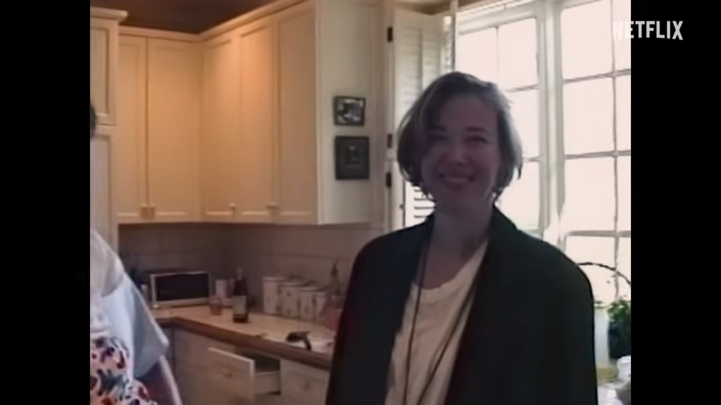 A smiling woman with short hair stands in a kitchen.