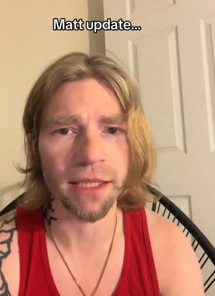 Bear Brown in a red tank top with a beard and medium-length blonde hair.