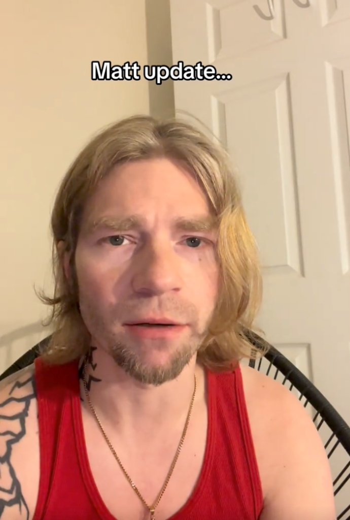 Matt Brown in a red tank top with a beard and long blond hair.