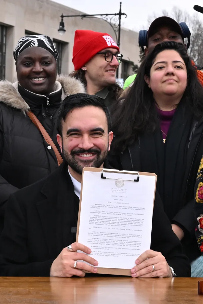 Mayor Mamdani smiles while holding Executive Order No. 7 establishing the Office of Mass Engagement.