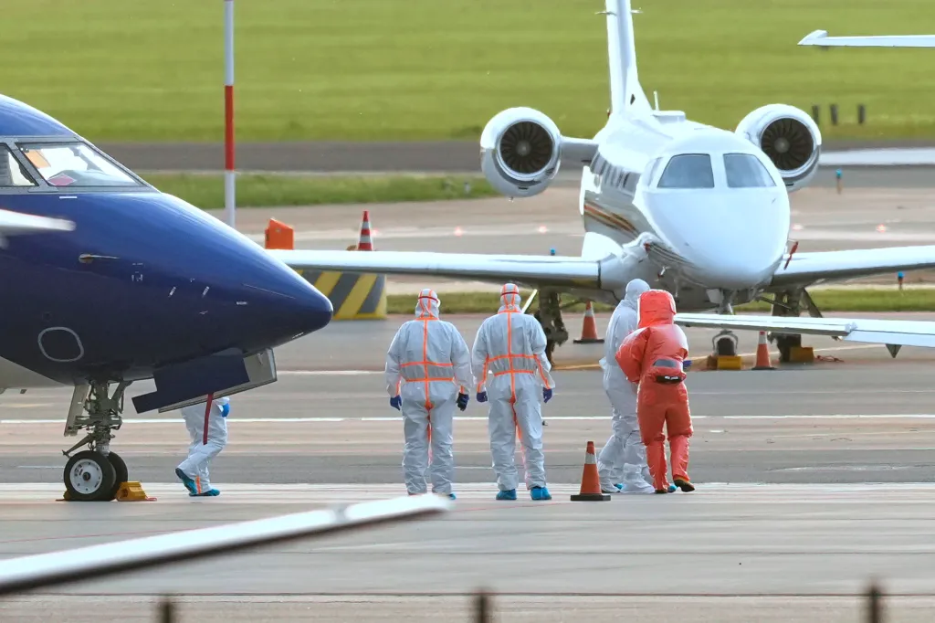 A passenger evacuated from the MV Hondius is escorted to an ambulance after landing in Amsterdam, Netherlands, on May 6, 2026.
