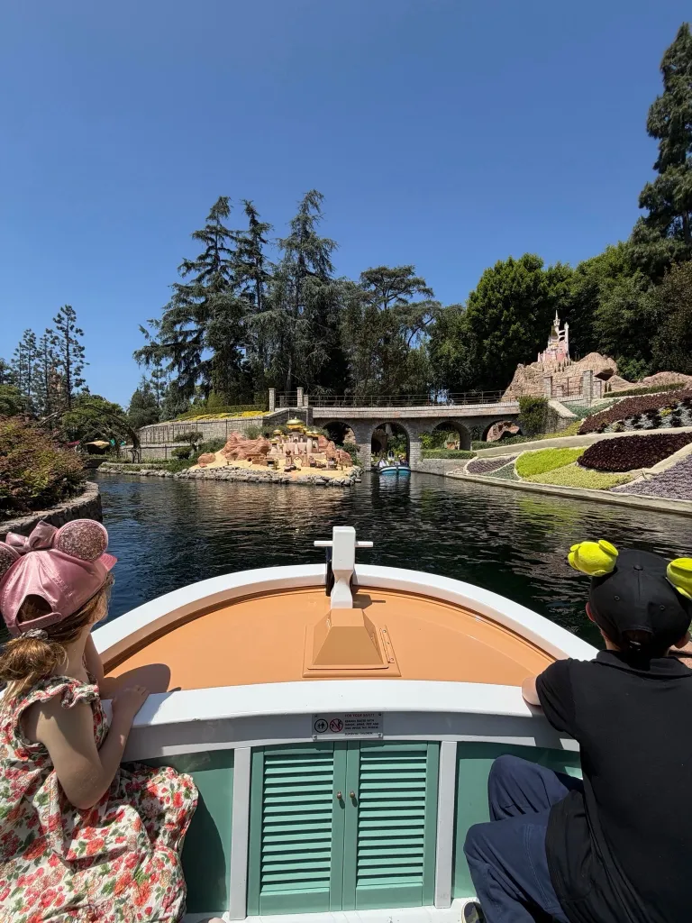 Two children in a boat ride looking at the scenery in Disneyland.
