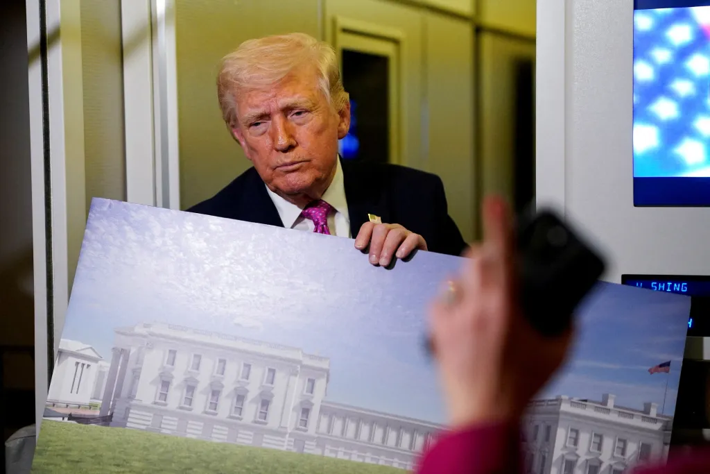 Donald Trump holds up renderings of the planned White House ballroom aboard Air Force One.