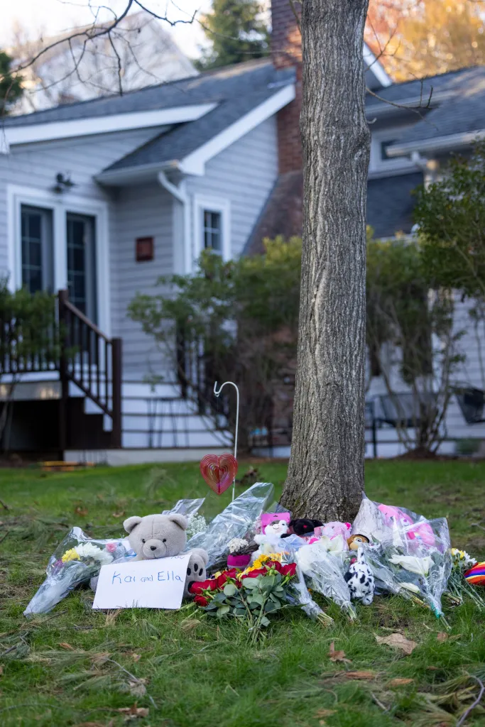 A memorial with flowers, stuffed animals, and a sign reading 