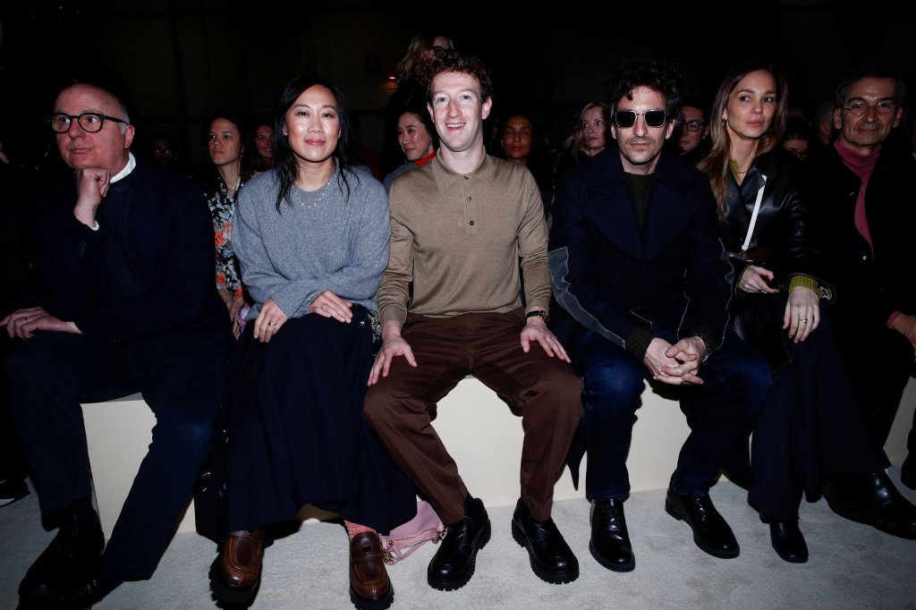 Mark Zuckerberg, in a brown top and brown pants, and Priscilla Chan, in a grey sweater and black pants, attend the Prada Fall/Winter 2026/2027 collection show.