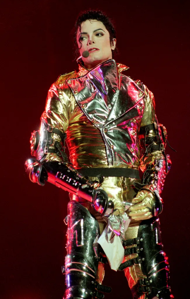 Michael Jackson performing in a metallic gold and silver suit with black accents, wearing a microphone headset.